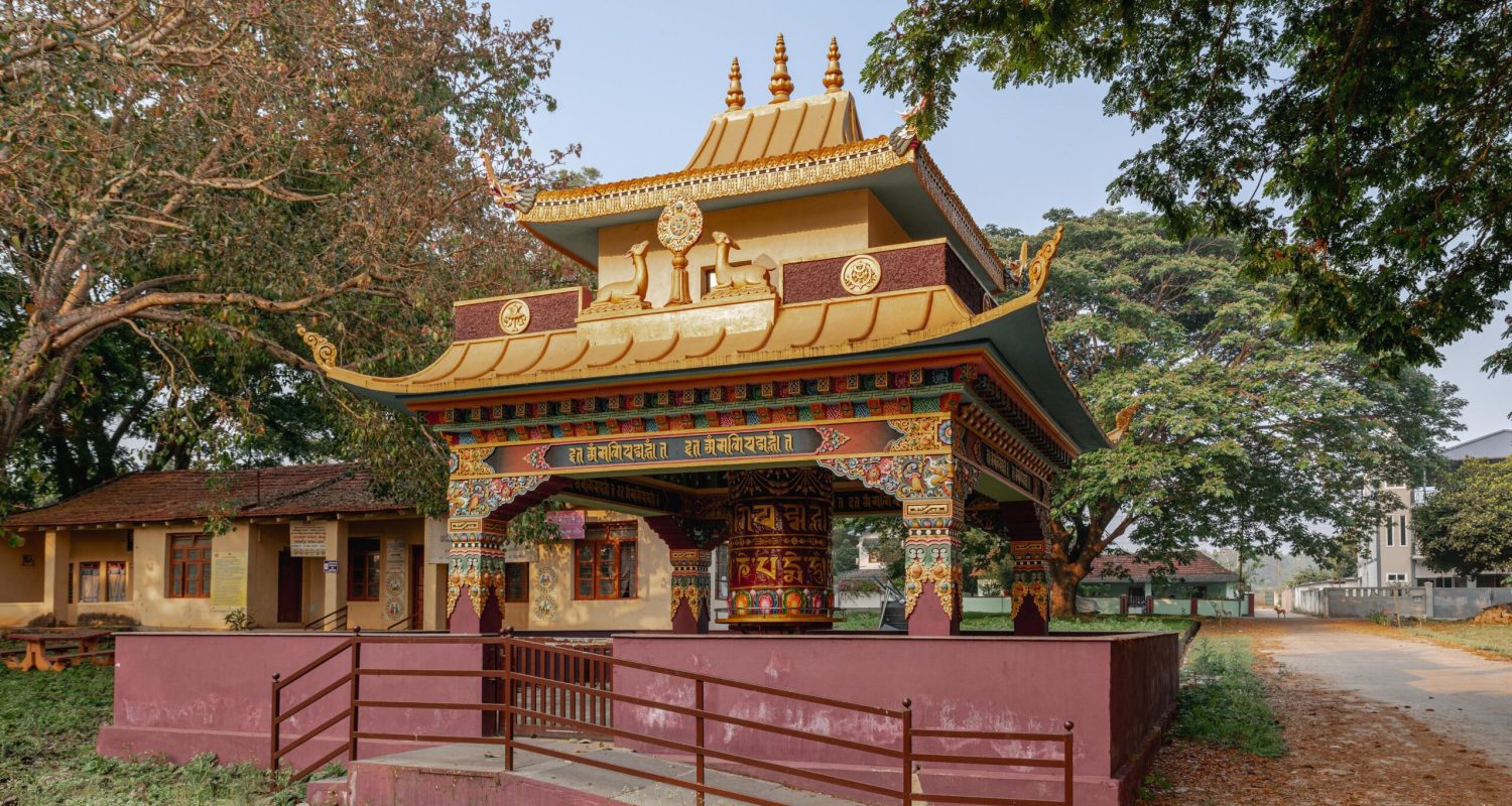 Vibrant Buddhist temple architecture in Bylakuppe, Karnataka, India, surrounded by lush greenery.