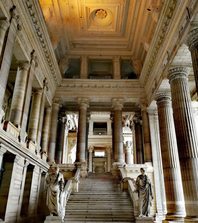 Neoclassical interior of the Law Courts of Brussels with grand columns and statues.